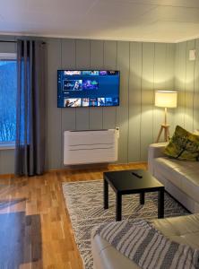 a living room with a couch and a tv on the wall at Villa Lyngenfjord in Olderdalen