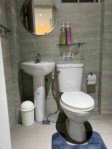 a bathroom with a toilet and a sink and a mirror at Fort Victoria Loft in BGC Wifi Netflix in Manila
