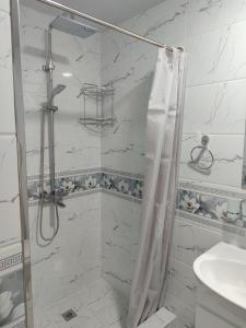 a white bathroom with a shower and a sink at Отель-музей in Tashkent