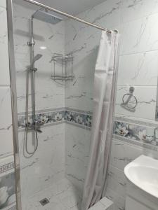 une salle de bain blanche avec une douche et un lavabo dans l'établissement Отель-музей, à Tachkent