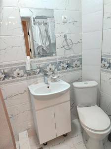 a white bathroom with a toilet and a sink at Отель-музей in Tashkent