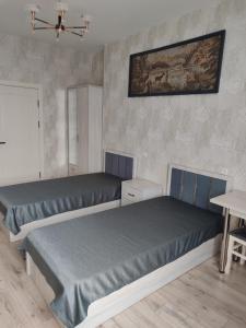 a bedroom with two beds and a painting on the wall at Отель-музей in Tashkent