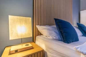1 cama con almohadas azules y mesita de noche con lámpara en 9 min to City Center via Metro 1BR 1LR with Balcony, en Viena