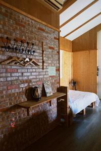 a room with a brick wall with a bed and a table at Red brick 642 B&B in Puli