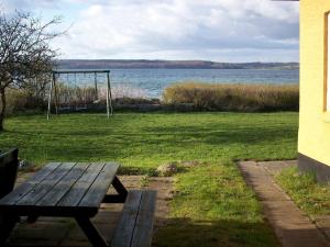 a picnic table in a field with a swing at 6 person holiday home in Aabenraa in Aabenraa