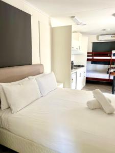 um quarto com uma cama branca e almofadas brancas em Sunset Beach Holiday Park em Geraldton