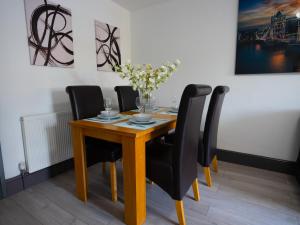 een eettafel met zwarte stoelen en een vaas met bloemen bij Central Apartment 3 Beds Near Station Fee Parking in Farnborough