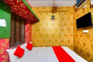 a bedroom with a bed with red pillows and a tv at Goroomgo Sri Jagannath Nibas Puri in Puri