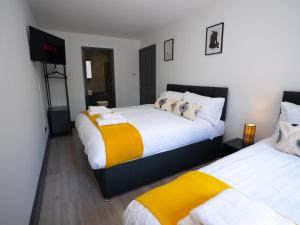 1 dormitorio con 2 camas con sábanas blancas y amarillas en Central Apartment 3 Beds Near Station Fee Parking en Farnborough
