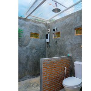 baño con aseo y pared de ladrillo en Quality Time Farmstay: Bamboo House, en Ban Pa Lau