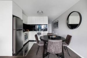 a kitchen with a black table and chairs and a mirror at The Skysill - A Sleek Inner city Sanctuary with Pool in Melbourne