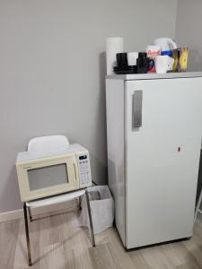 a microwave sitting on a stool next to a refrigerator at Brand New 2 Bedroom Basement Suite with Wifi in Edmonton