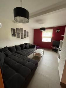 uma sala de estar com um sofá preto e uma parede vermelha em Maison avec piscine em Hoerdt