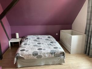 um quarto com paredes roxas e uma cama e um berço em Maison avec piscine em Hoerdt