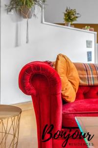 eine Person, die auf einer roten Couch im Wohnzimmer sitzt in der Unterkunft Sentier Suite - Chic 1BR-1BA,Heart of Edinburgh, Old Town by Bonjour Residences Edinburgh in Edinburgh