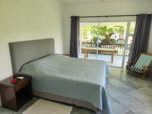 a bedroom with a bed and a balcony with a table at Fairy-Tern Chalets Cerf Island in Cerf Island