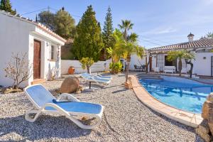 un patio trasero con sillas y una piscina en Casa Blanca, en Torrox