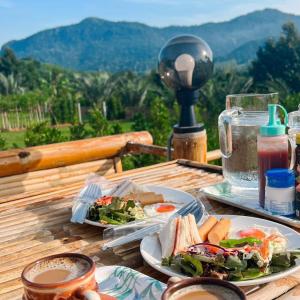 two plates of food on a wooden table with a view at Quality Time Farmstay: River House in Ban Pa Lau