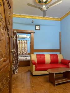 a living room with a red couch and a bed at VM Residency in Yelagiri