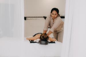 a woman sitting on a bed with a woman getting her hair cut at Casa Art Ubud in Ubud