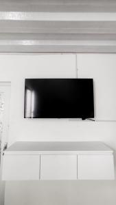 telewizor z płaskim ekranem wiszący na białej ścianie w obiekcie Kost Harian Semarang Murah w mieście Semarang