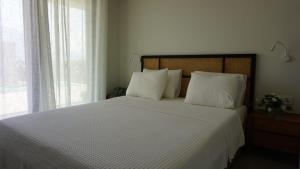 um quarto com uma grande cama branca com almofadas brancas em Villa Isa em Pogoniá