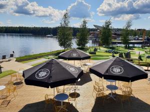 zwei Tische und Stühle mit Sonnenschirmen neben einem See in der Unterkunft Bella Lake Resort in Kuopio