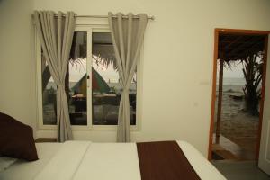 1 dormitorio con cama y ventana con vistas a la playa en Havana Beach House, en Alleppey