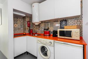 eine Küche mit einer Mikrowelle, einer Waschmaschine und einem Trockner in der Unterkunft Apartamento com pátio em frente praia in Paço de Arcos