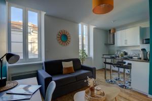 a living room with a couch and a kitchen at Le Tournassin-Balcon-Stationnement gratuit in Bourg-en-Bresse