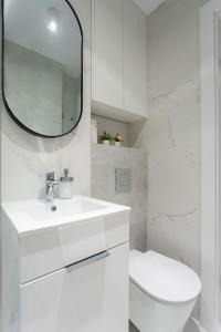 uma casa de banho branca com um WC e um espelho. em Grzybowska Rooms by Sofija em Varsóvia