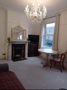 uma sala de estar com um lustre, uma mesa e uma lareira em North Street Flat em Bristol