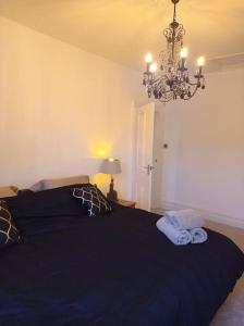 a bedroom with a black bed and a chandelier at North Street Flat in Bristol