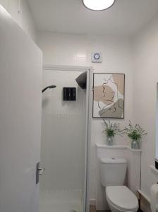 a white bathroom with a toilet and a shower at North Street Flat in Bristol