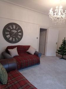 a living room with a couch and a clock on the wall at North Street Flat in Bristol