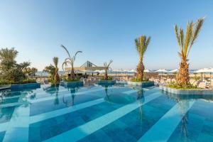 貝萊克的住宿－Kirman Belazur Resort & Spa，一座棕榈树和遮阳伞的游泳池