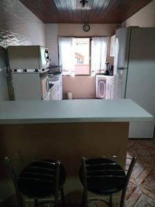 a kitchen with a counter and two chairs and a refrigerator at Casa linda e aconchegante para hóspedes.(Studio) in Joinville
