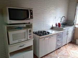 a kitchen with a microwave and a microwave oven and a stove at Casa linda e aconchegante para hóspedes.(Studio) in Joinville