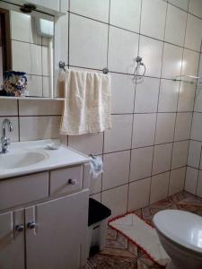 een badkamer met een wastafel, een toilet en een spiegel bij Casa linda e aconchegante para hóspedes.(Studio) in Joinville