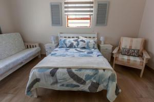 a bedroom with a bed and a chair at Surf n Sea Beachfront Holiday Home in Jeffreys Bay +29 photos