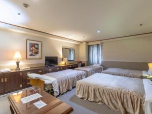 um quarto de hotel com três camas e uma televisão de ecrã plano em Tabist Hotel Liberty Plaza em Sakai