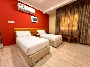 two beds in a hotel room with red walls at Remal Ibri hotel in ‘Ibrī