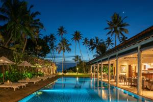 einen Pool vor einem Resort mit Palmen in der Unterkunft Taru Villas The Long House - Bentota in Bentota
