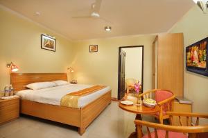 a bedroom with a bed and a table and a chair at Sun Hotel-Haridwar in Haridwār