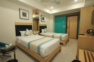 a hotel room with two beds and a kitchen at SN Blu Hotel in Ahmedabad