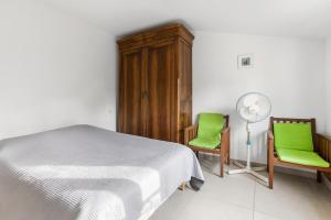 een slaapkamer met een bed en 2 stoelen en een ventilator bij Les Terrasses de Cogolin in Cogolin