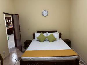 1 cama con 2 almohadas y reloj en la pared en Hills House Galle, en Galle