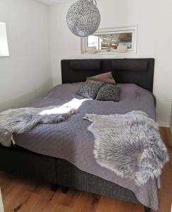 Una cama con una manta gris y almohadas. en Årsta strand en Estocolmo
