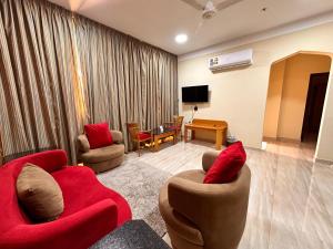 ein Wohnzimmer mit 2 roten Stühlen und einem TV in der Unterkunft Remal Ibri hotel in Ibri