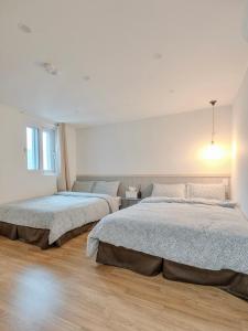 two beds in a white bedroom with at Harmony Stay in Seoul